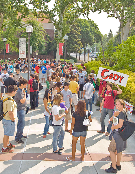 Prospective students gather outside Bell Memorial Union. One man holds up a sign that says "CODY."