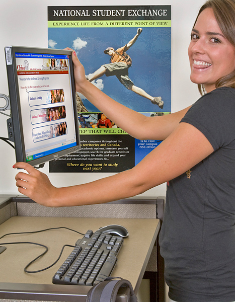 Woman grins and adjusts computer monitor.