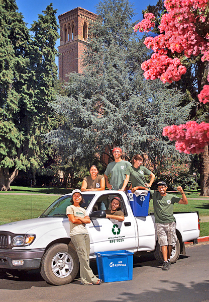 Six AS Recycling students stand with truck with bell tower behind and blossoms front right.