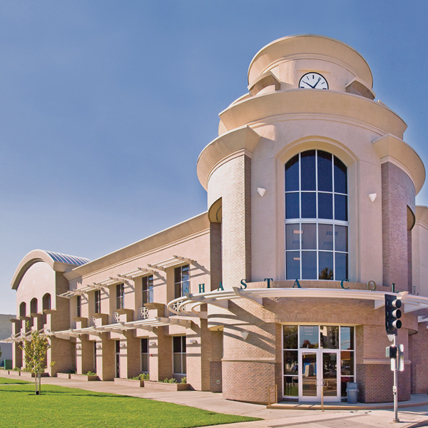 Modern building, entrance right, is illuminated on left side by sunshine on a clear day.