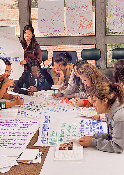 EOP students hover over posters working collectively on a project inside Meriam Library.