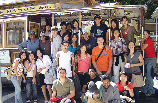 A large group of international students pose nest to a street car in San Francisco, CA.