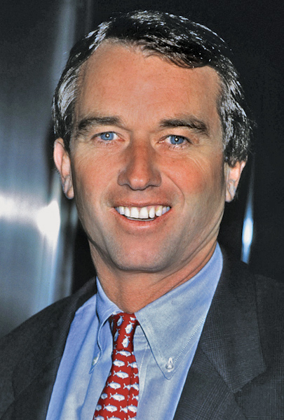 Robert Kennedy, Jr. poses in a grey suit with a blue shirt and red fish tie.