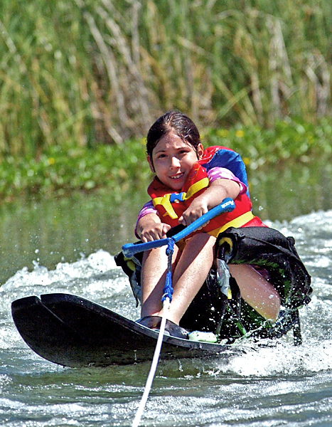 Young girl holds on to a tow rope while enjoying some water sport fun.