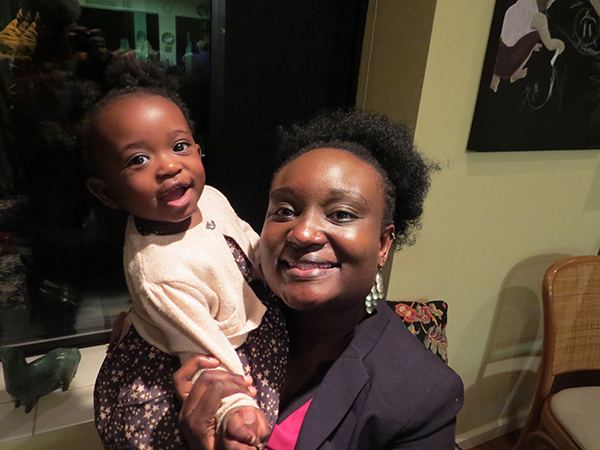 A mother and her toddler-aged daughter smile and pose for the camera.