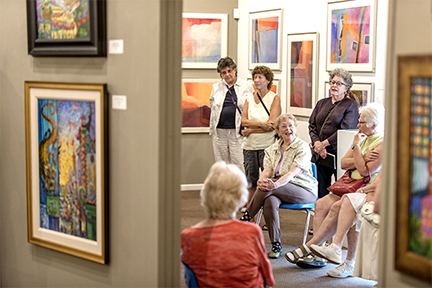 Several women, some seated, some standing, gather at what appears to be an art museum.