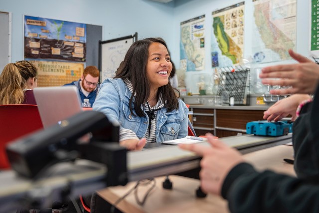 A female student sits at a lab table.